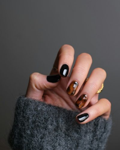 A hand with black and tortoiseshell patterned nails