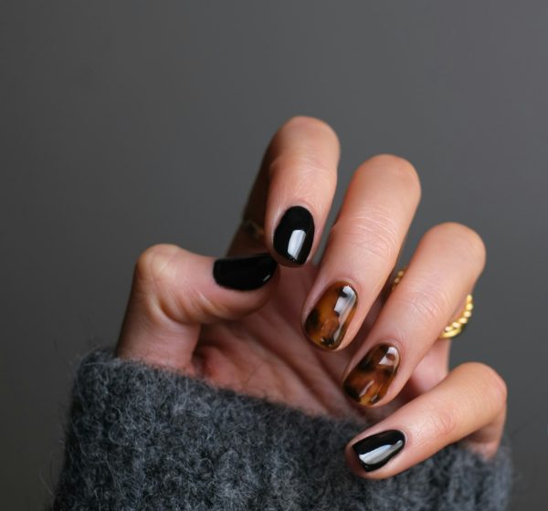 A hand with black and tortoiseshell patterned nails