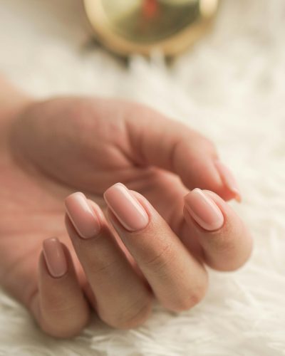 A hand with light pink manicured nails
