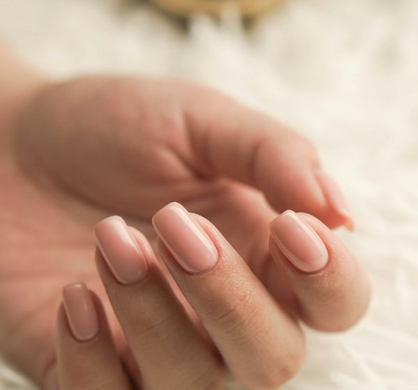 A hand with light pink manicured nails